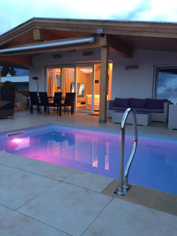 蒂罗尔-泽费尔德Haus Eibl的一座位于房子前方的紫色照明游泳池