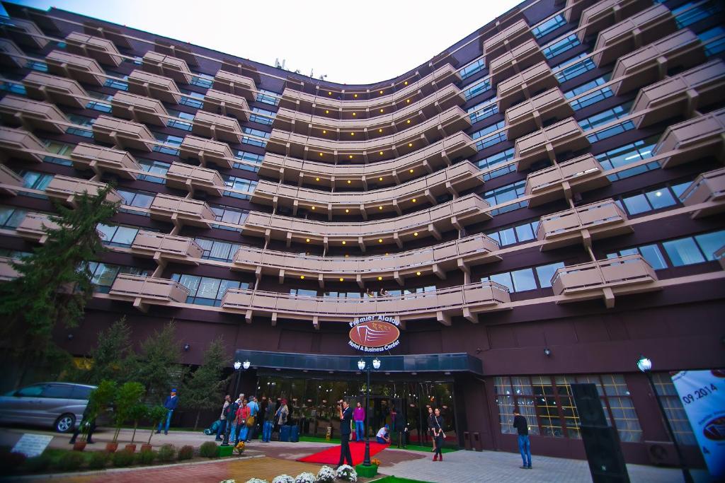 阿拉木图高级阿拉套酒店的一座大型建筑,外面的人