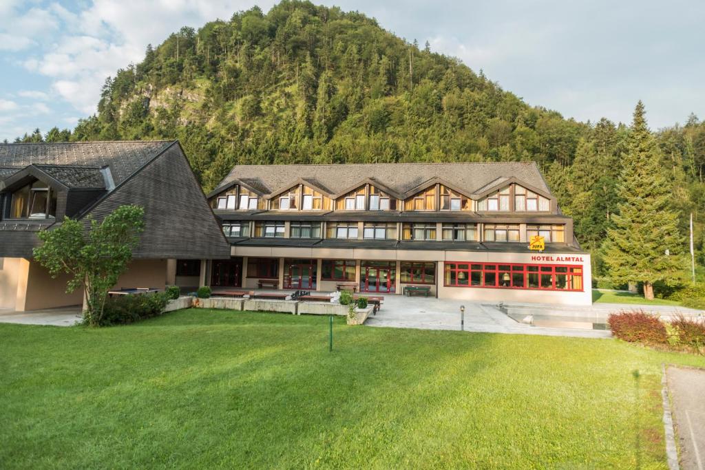 格吕瑙JUFA Hotel Grünau im Almtal的山前的大房子,有大草坪