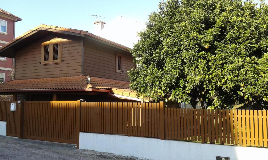 坎加斯德穆拉索Casa de Madera的棕色的房子,有栅栏和一棵树