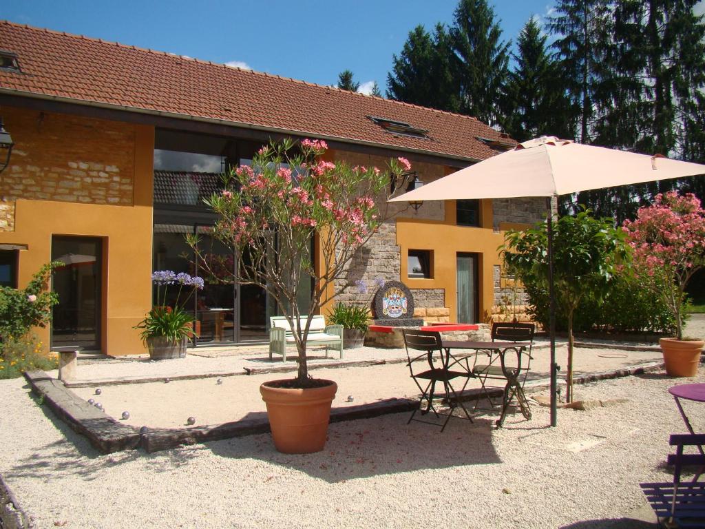 Charrey-sur-Saônela Grange de Félicie的庭院配有遮阳伞和桌椅。