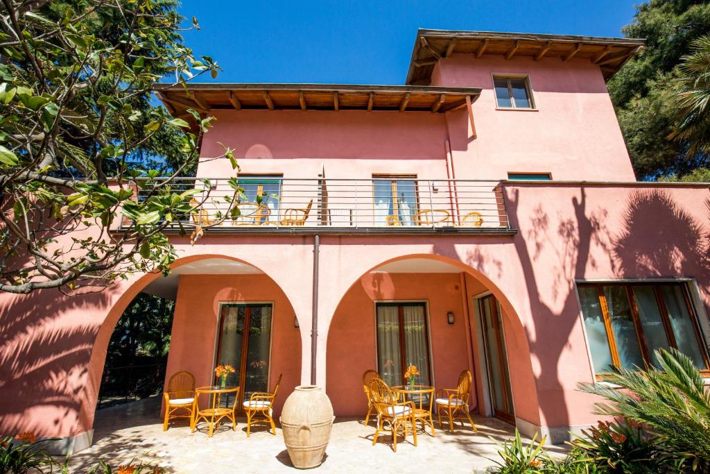 索伦托索伦托洛萨别墅酒店的粉红色的房子设有阳台和桌椅