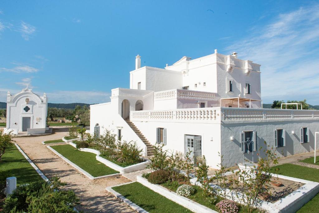 法萨诺Masseria San Giovanni - Epoca Collection的一座白色的大房子,前面设有一个花园