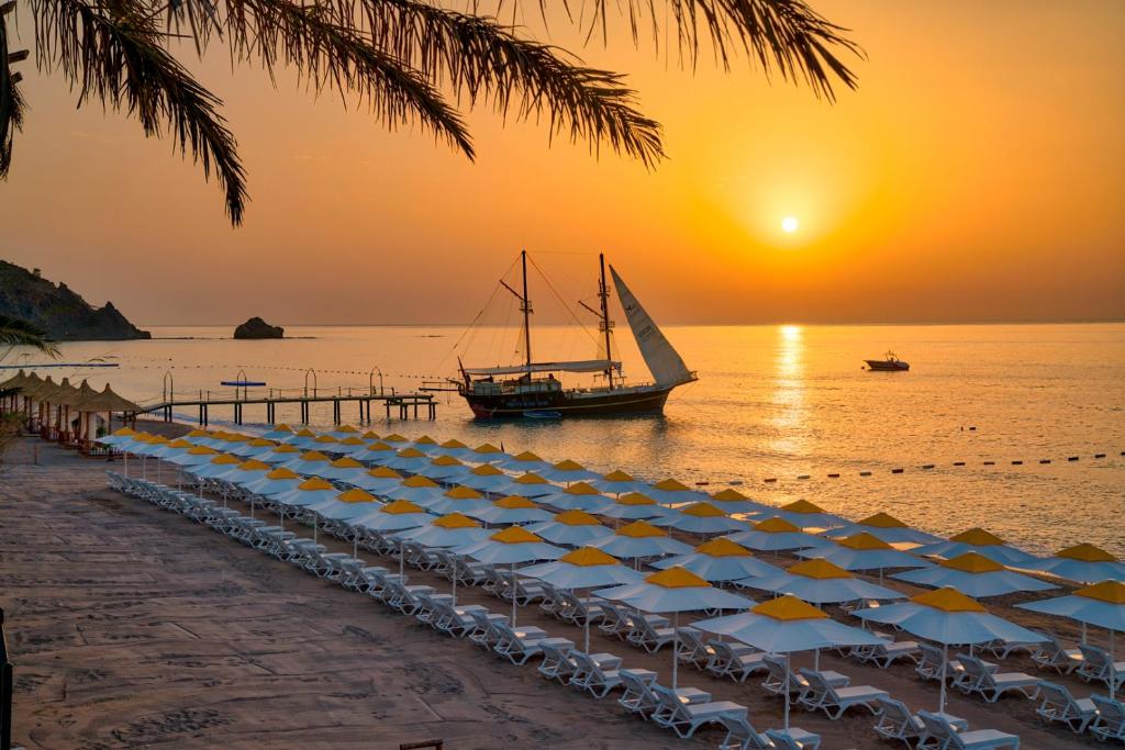 特基罗瓦海盗沙滩俱乐部酒店的海滩上的一群遮阳伞和一艘船