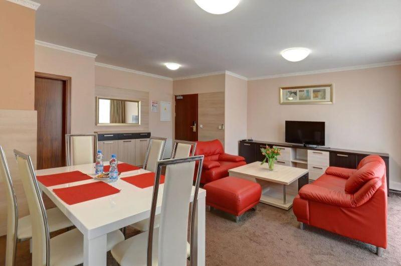 特普利采特普利莱广场酒店的客厅配有桌子和红色椅子