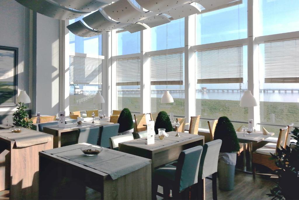 威廉港挪德熙威廉港酒店的餐厅设有桌椅和大窗户。