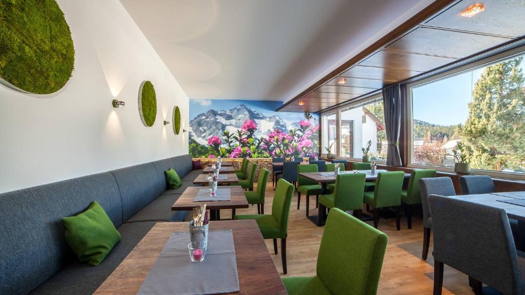 蒂罗尔-泽费尔德Boutique Hotel Olympia的餐厅设有桌子和绿色椅子以及窗户。