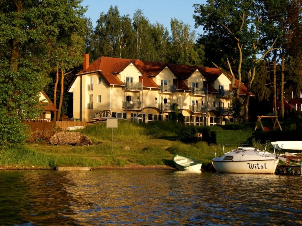 克雷托维尼Biały Łabędź的水面上的大房子,前面有船