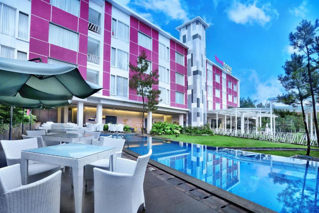 加鲁特希曼努克贾璐酒店的酒店庭院设有桌椅和游泳池。