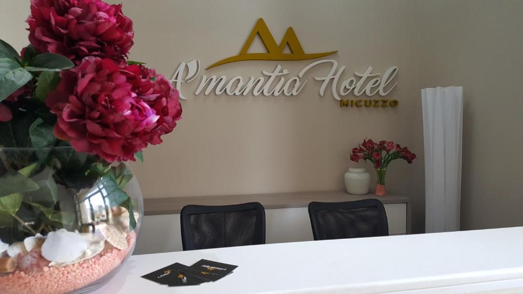 阿曼泰阿A'MANTIA HOTEL的花瓶在桌子上,有aania酒店标志