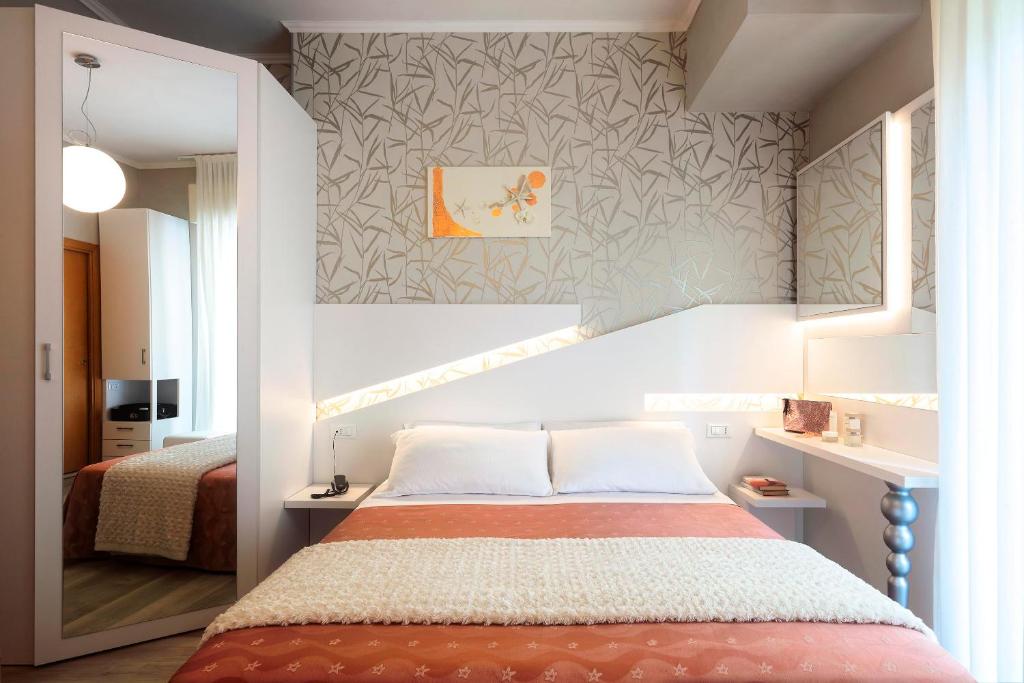 里米尼Hotel Ombretta Mare的一间卧室设有一张床和一面墙