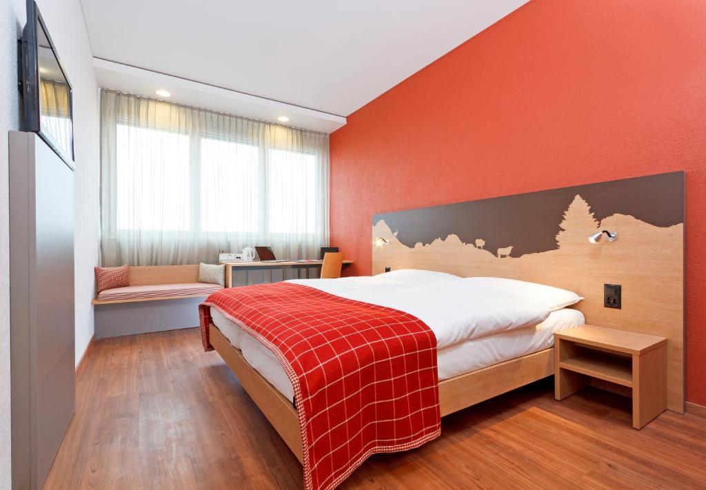 楚格瑞士祖格品质酒店的一间卧室配有一张带橙色墙壁的大床