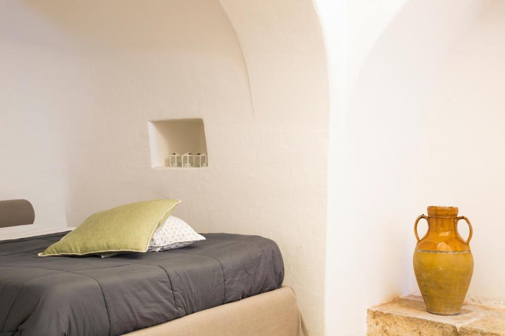 阿尔贝罗贝洛Il Trullo del viaggiatore的一间卧室,配有一张床和一张桌子上的花瓶