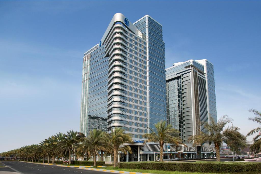 阿布扎比珍珠罗塔纳首都中心酒店的一座高大的建筑,前面有棕榈树