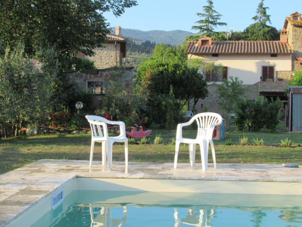 科尔托纳Podere Casorbica的两把白色椅子坐在游泳池旁