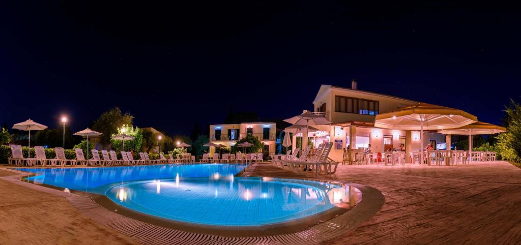 卡沃斯Yianetta Hotel Apartments的游泳池在晚上提供椅子和遮阳伞