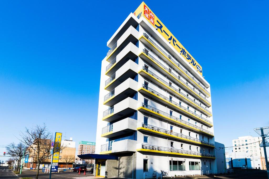 钏路Super Hotel Kushiro Natural Hot Spring的一座高大的建筑,旁边有一个标志