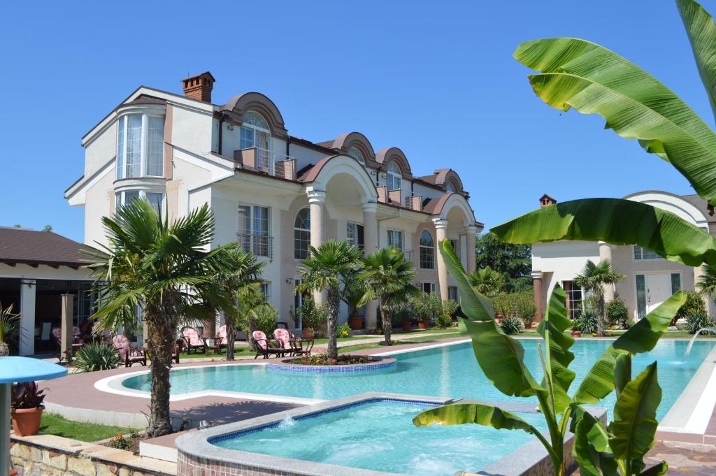 奥赫里德亚历山大别墅及水疗酒店的一座带游泳池和棕榈树的大型建筑