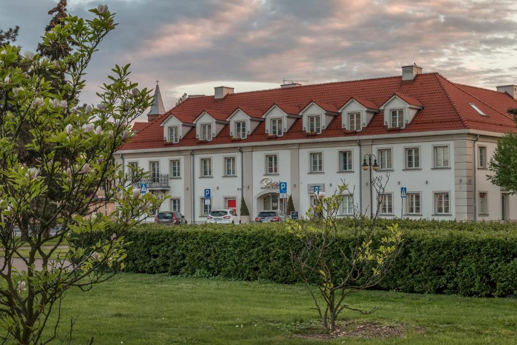 弗沃茨瓦韦克罗泽比基酒店的一座白色的大建筑,有红色的屋顶