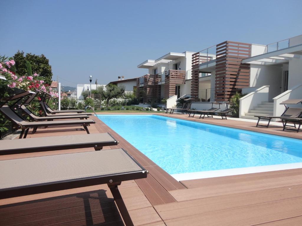 巴多利诺Bio Suites PACINOTTI的一座带躺椅的游泳池,毗邻一座建筑
