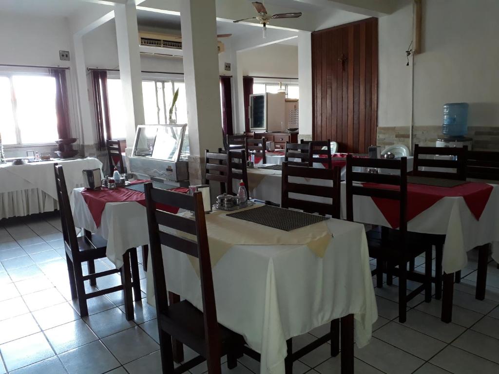 马拉巴Plaza Hotel的餐厅设有桌椅,配有红色和白色的桌布
