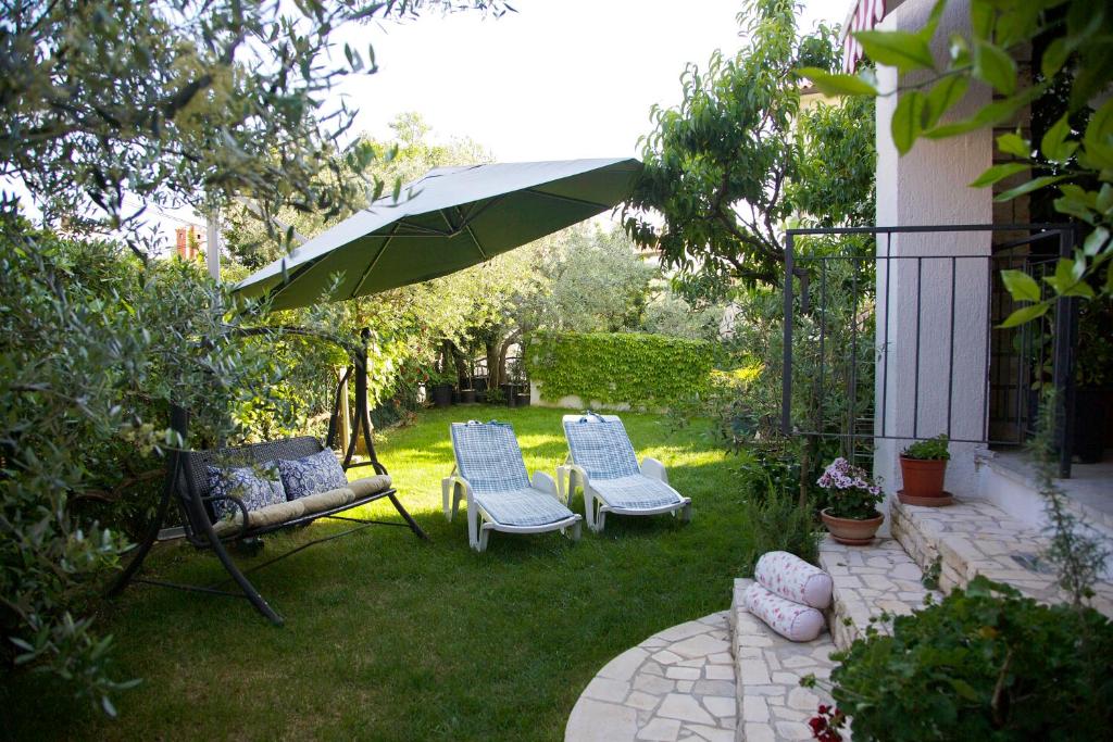 罗维尼Melanija 2的庭院配有两把椅子和一把遮阳伞