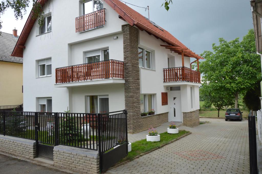 赫维兹Varga Apartman Hévíz的白色的房子,设有红色的阳台和车道