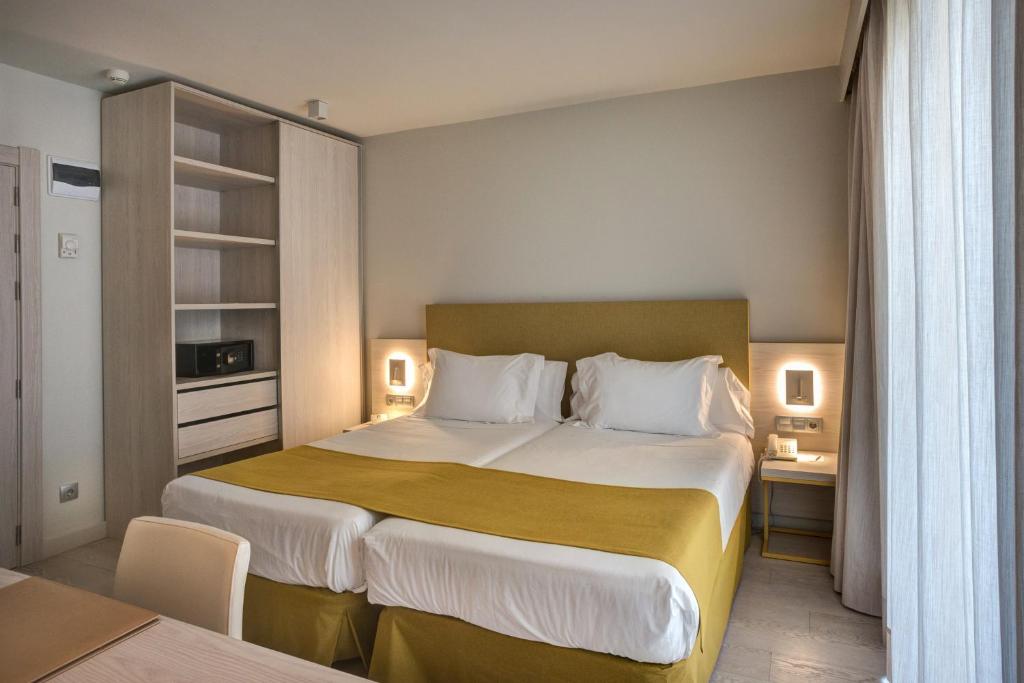 罗萨斯Hotel Mediterraneo的酒店客房设有一张大床和一张书桌。