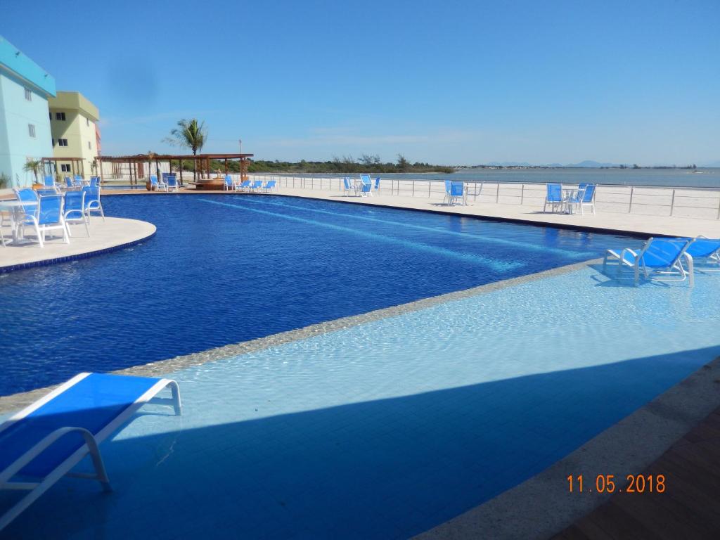 阿拉亚尔-杜卡布Flat entre Mar e Lagoa的一个带蓝色椅子和海洋的大型游泳池