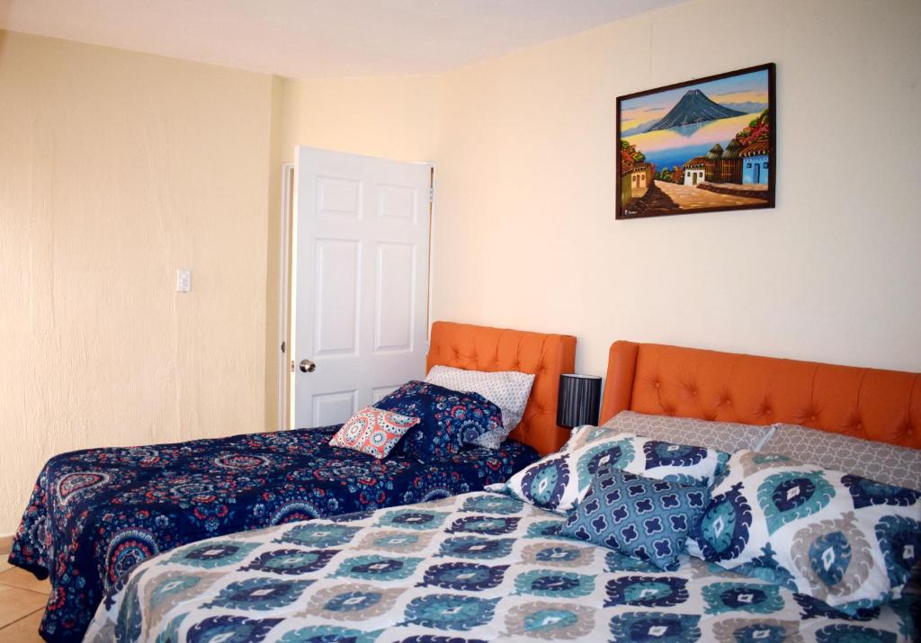 危地马拉Laguna Sky的卧室配有两张床,墙上挂着一幅画