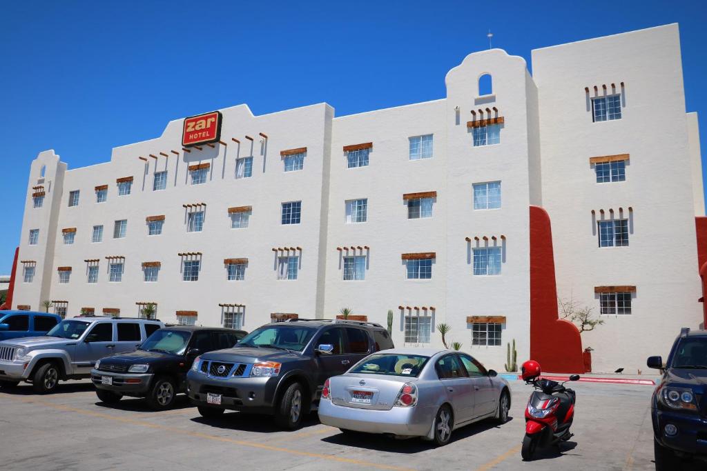 拉巴斯扎尔拉巴斯酒店的一座白色的大建筑,汽车停在停车场