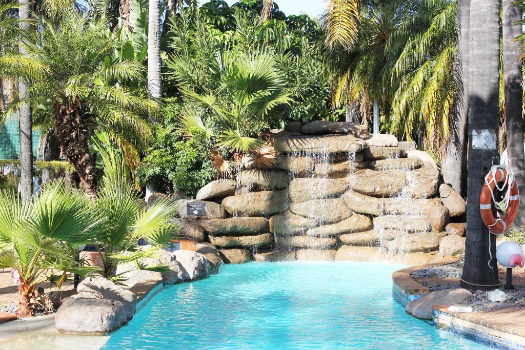 天鹅山天鹅山度假酒店的一座拥有瀑布和棕榈树的度假村内的游泳池