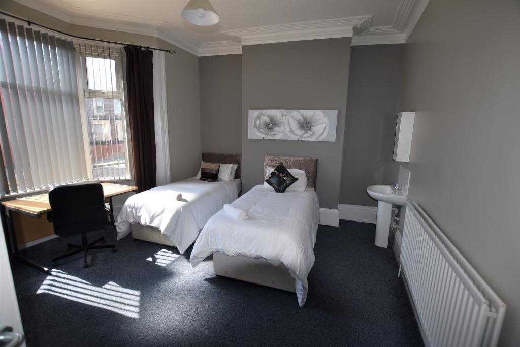 桑德兰Western Hill的一间卧室设有两张床、一张桌子和一个窗口。