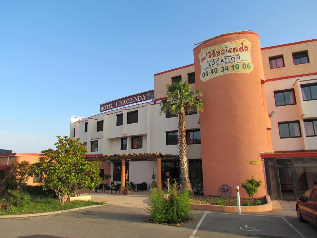 沙托纳莱马尔蒂盖Hôtel L'Hacienda的一座建筑前有棕榈树的酒店