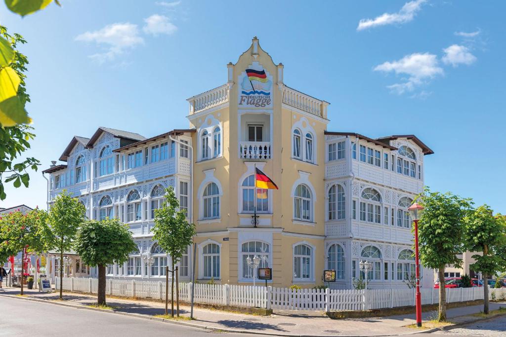 宾茨德意志旗酒店的白色的黄色建筑,有白色的栅栏