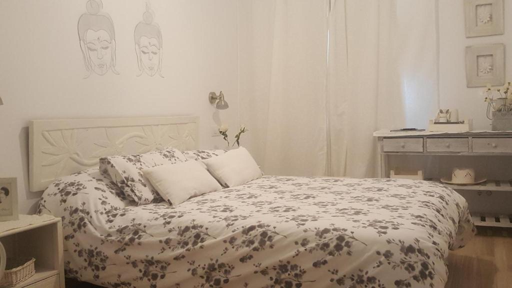 德拉塞尔瓦港Fonda Felip的白色卧室配有带花卉棉被的床