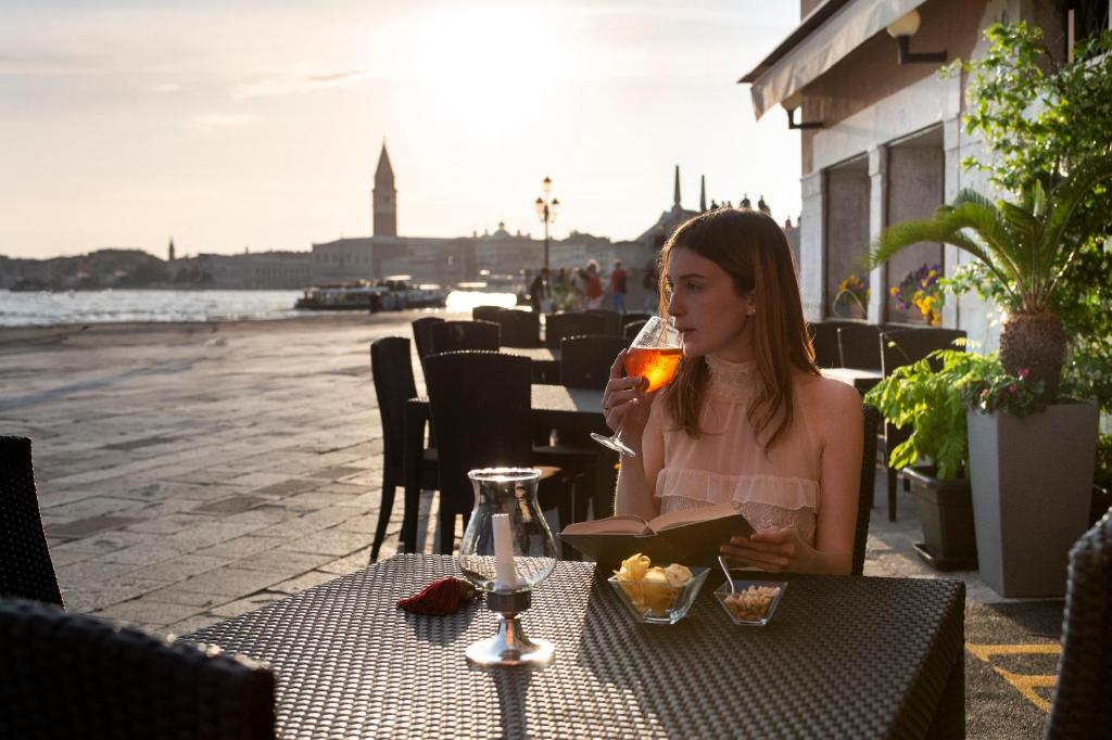 威尼斯布奇托罗酒店的坐在桌子旁喝一杯酒的女人
