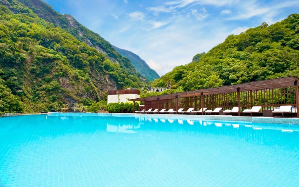 Fushi太鲁阁晶英酒店的一个带椅子的游泳池,背景是群山