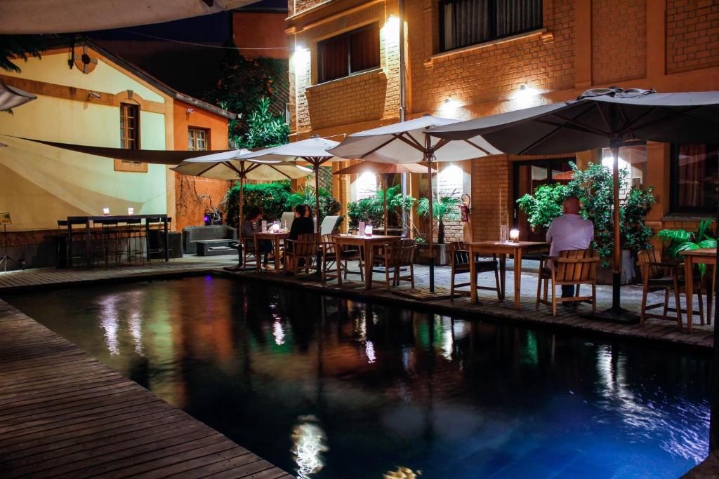 塔那那利佛萨卡曼加酒店的一间带桌子和遮阳伞的餐厅以及一个游泳池