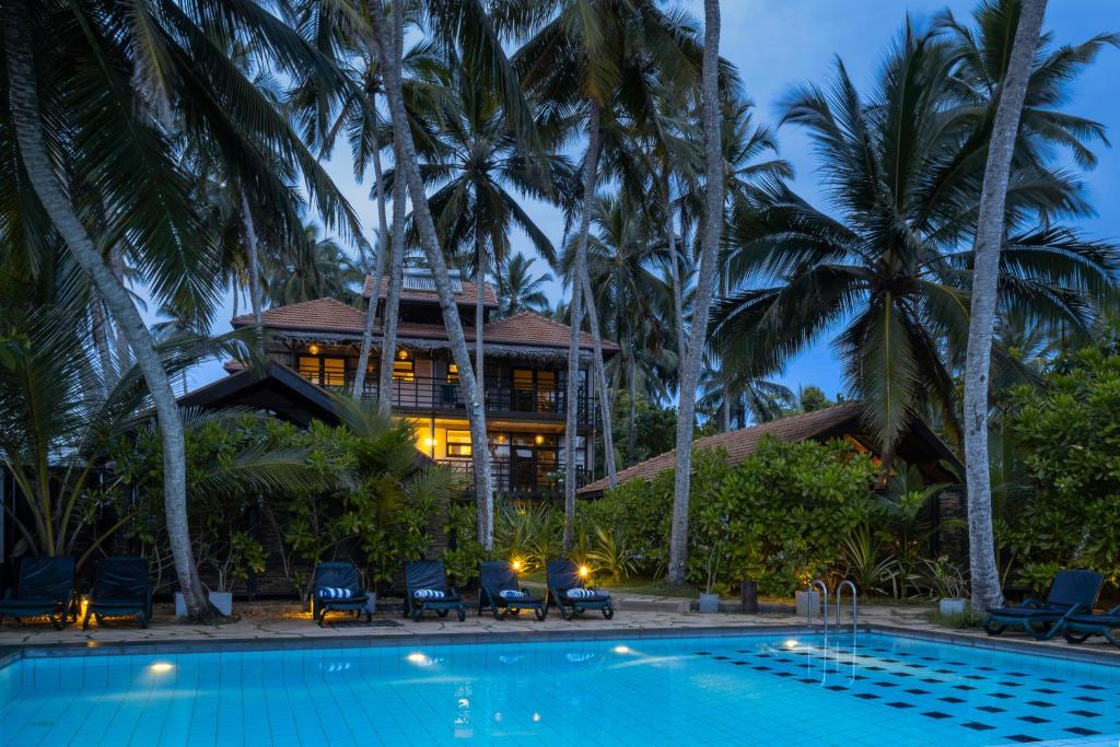 坦加拉七只海龟酒店的一座带游泳池的度假村,位于一座房子前