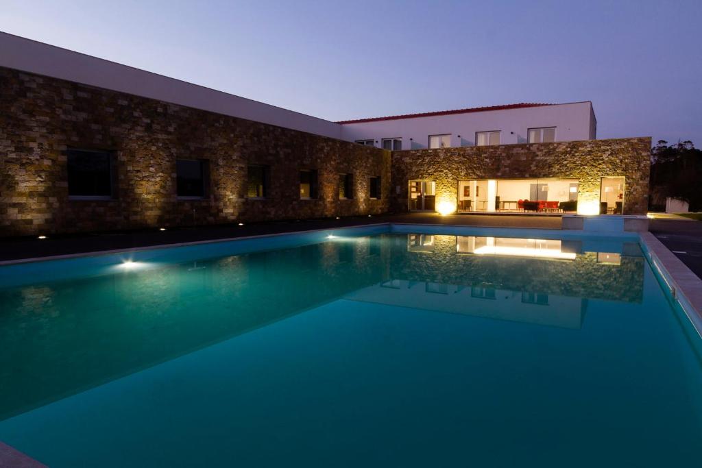 奥比多斯Hotel Vila D'Óbidos的一座游泳池,在晚上在建筑物前