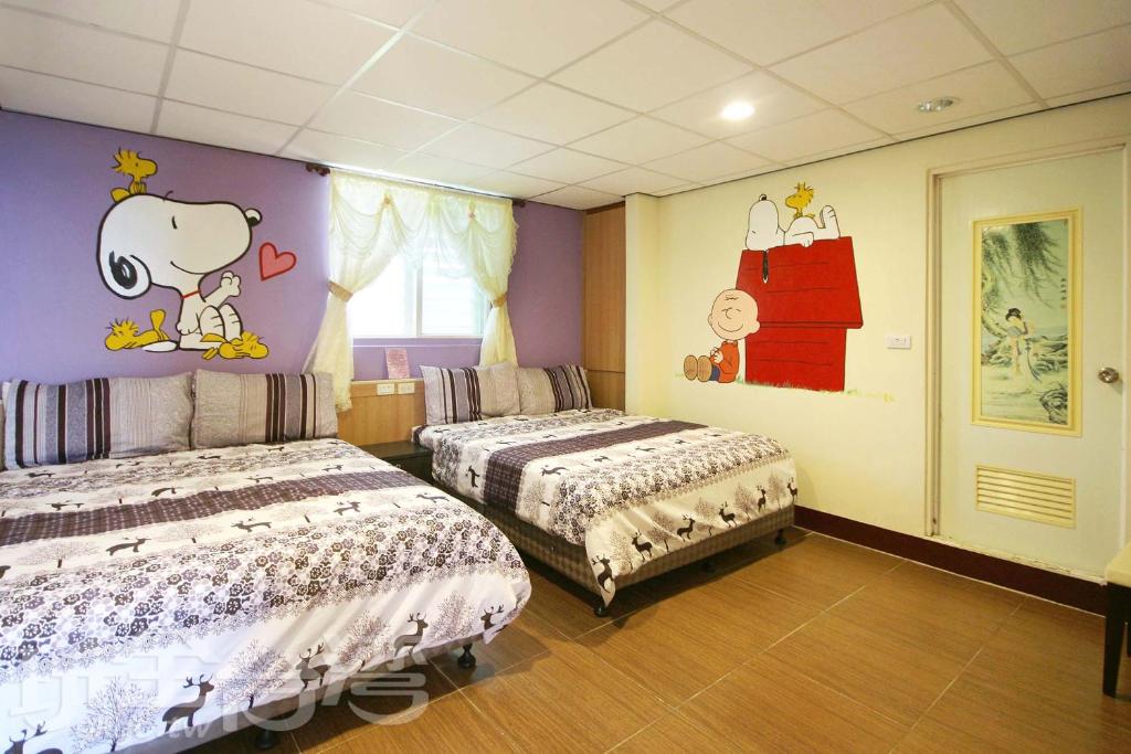 绿岛绿岛禾风旅栈的一间卧室设有两张床,墙上有漫画。