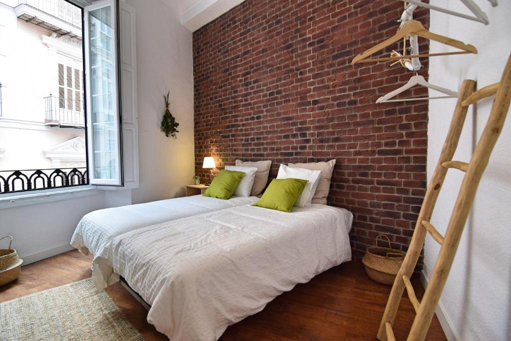 马拉加BRUNO´S HOME (OLD TOWN)的一间卧室设有砖墙和一张带绿色枕头的床