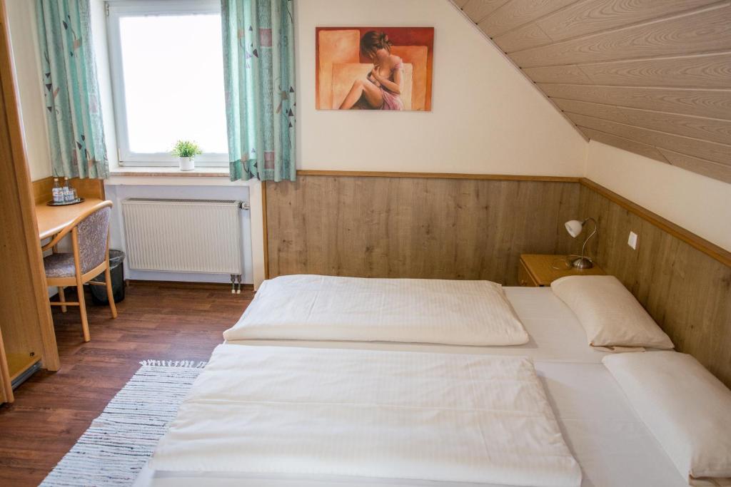 Waldstetten盖斯豪弗兹姆奥斯恩酒店的一间卧室设有两张床、一张桌子和一个窗口。