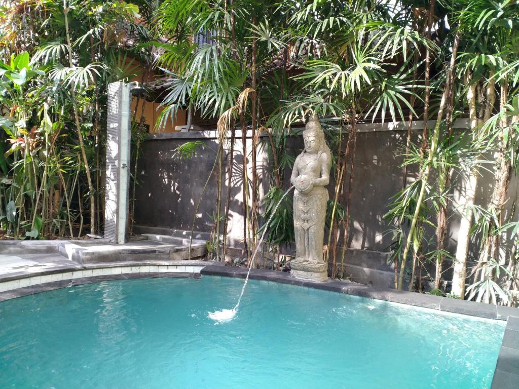 乌布彭杜克巴布家园酒店的游泳池中的喷泉,设有雕像