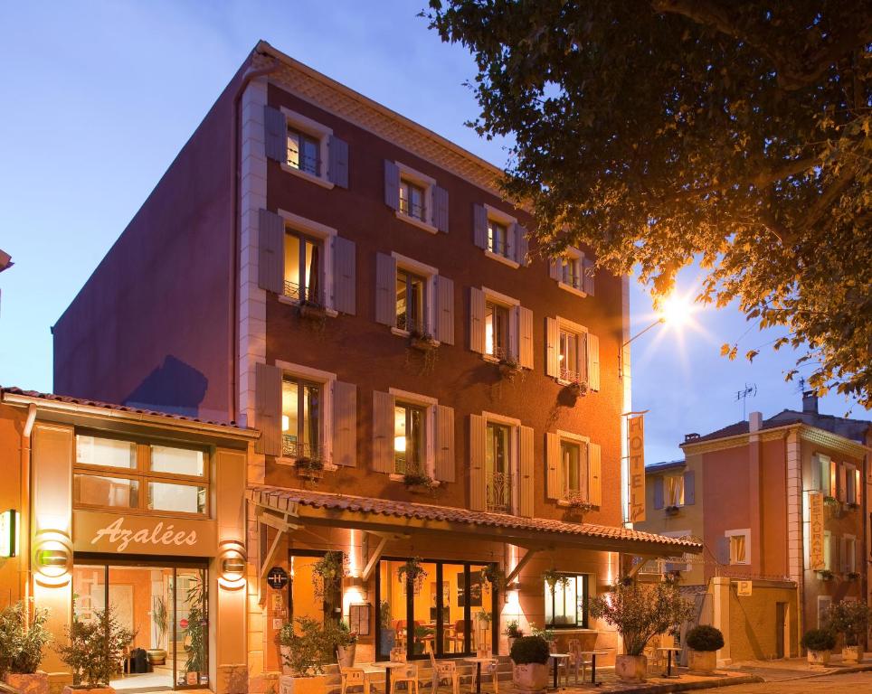 罗纳河畔的图尔农Logis Hôtel Restaurant Azalées的街道上一座建筑,前面有桌子