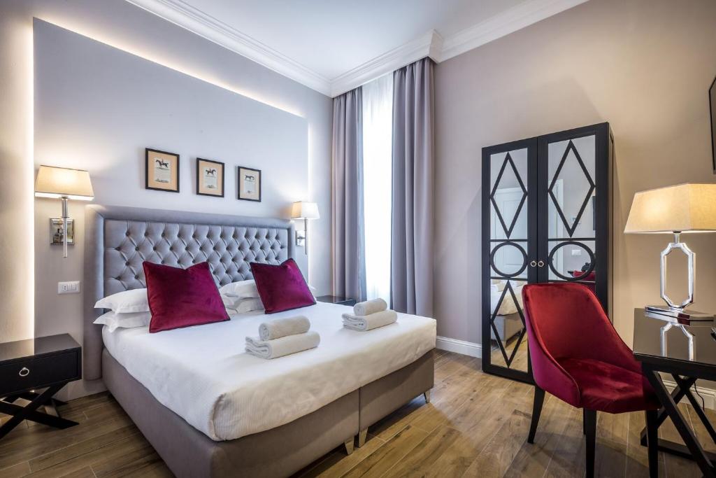 佛罗伦萨Hotel Emma Small Luxury Hotel的一间卧室配有一张大床和一张红色椅子