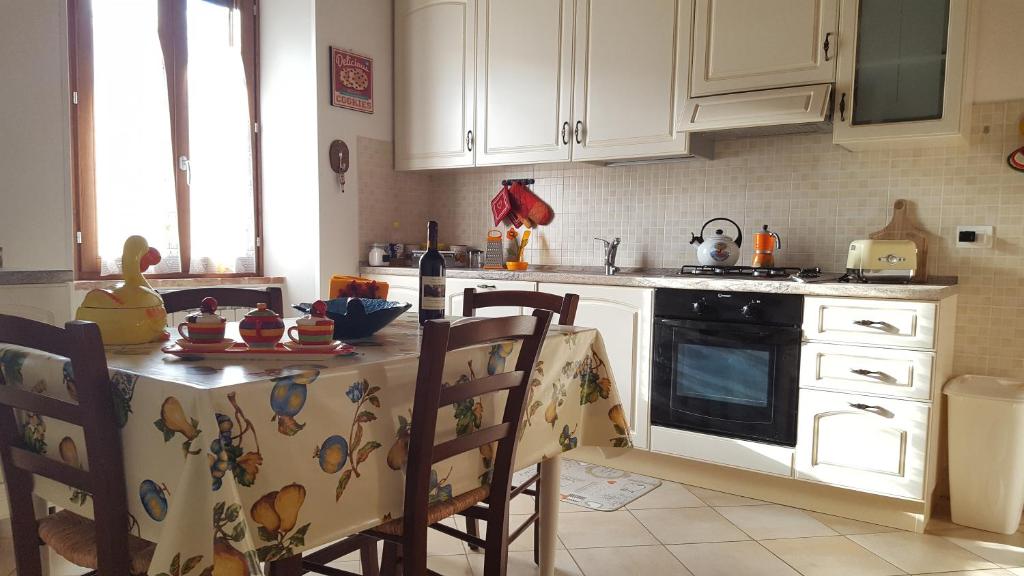 罗西亚Borgo Rosia Holiday House的厨房配有白色橱柜和桌椅