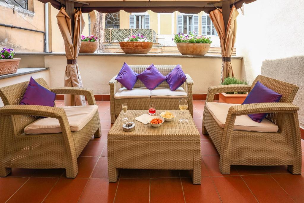 罗马历史套房酒店的庭院配有两把椅子和一张带紫色枕头的桌子。