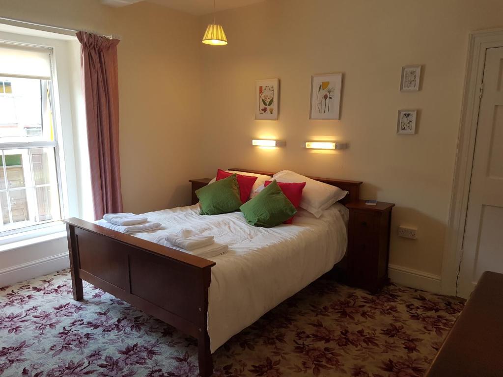 香农河畔卡里克Bridge House的一间卧室配有带绿色和红色枕头的床